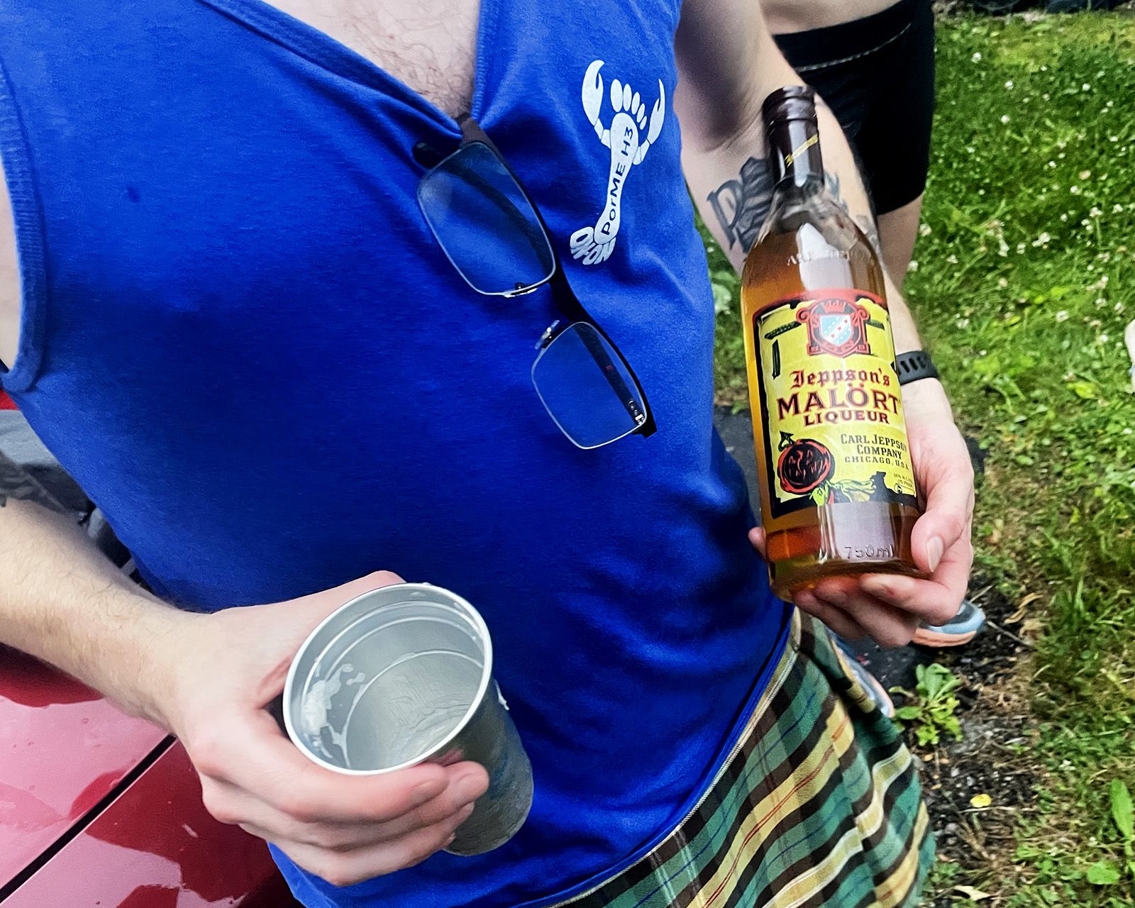 A hasher in a PorMEH3 tank top holding a bottle of Malört and a cup