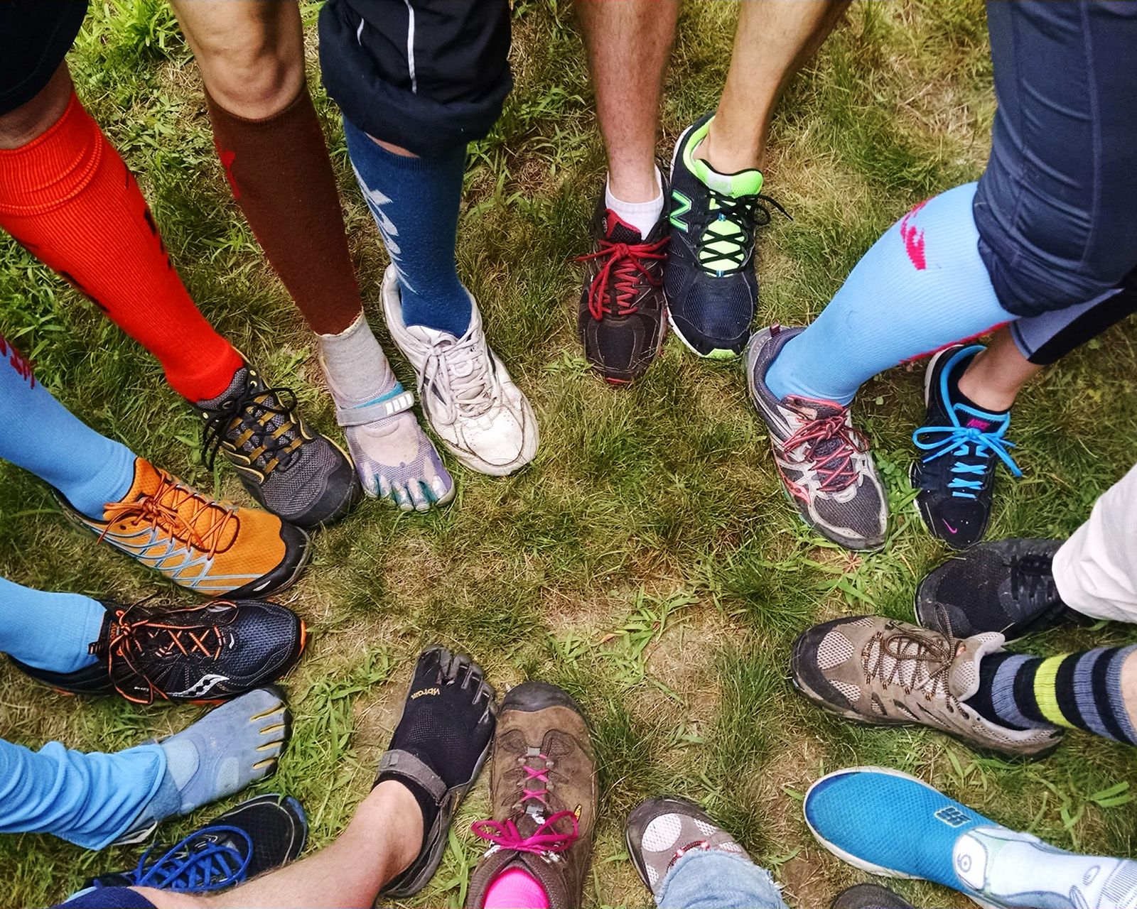A circle of hashers' feet in bright socks and muddy running shoes