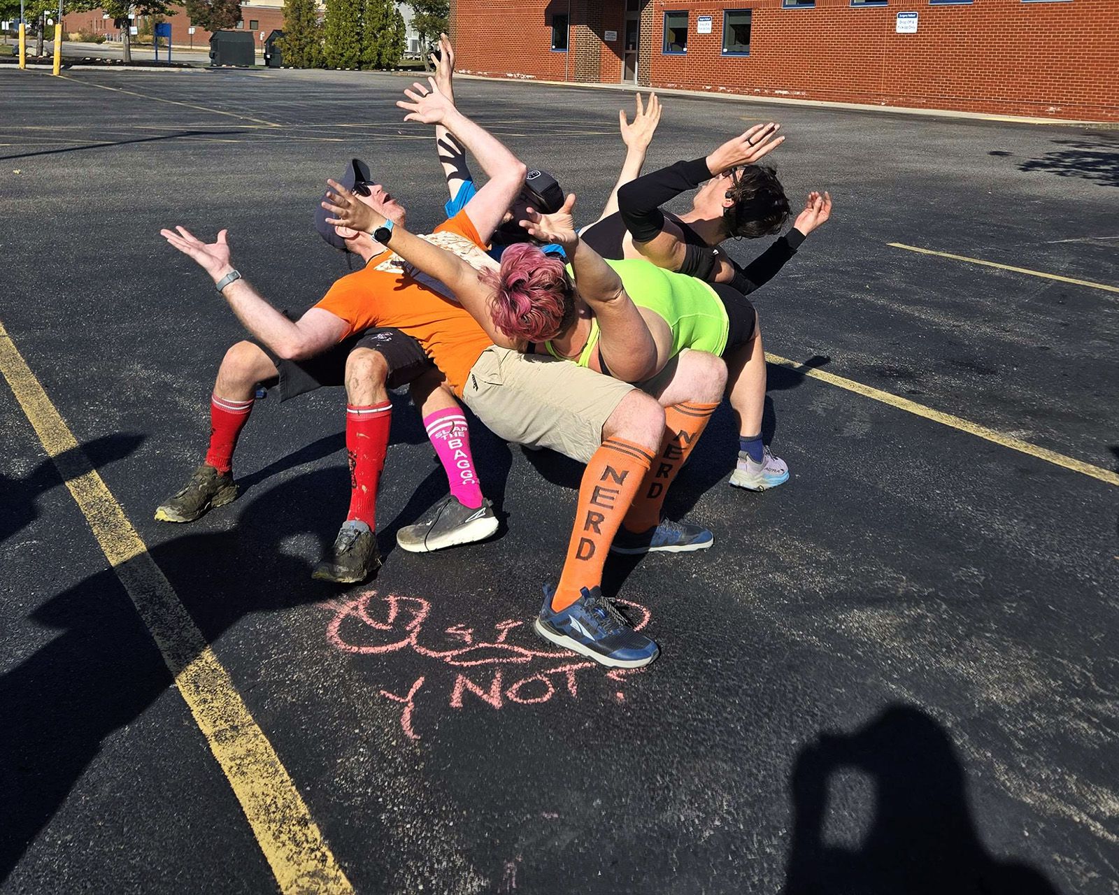 Hashers striking a pose in a parking lot beside a chalked "Y Not?"